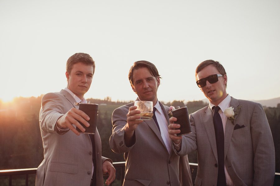 Groomsmen with drinks toasting the camera at sunset